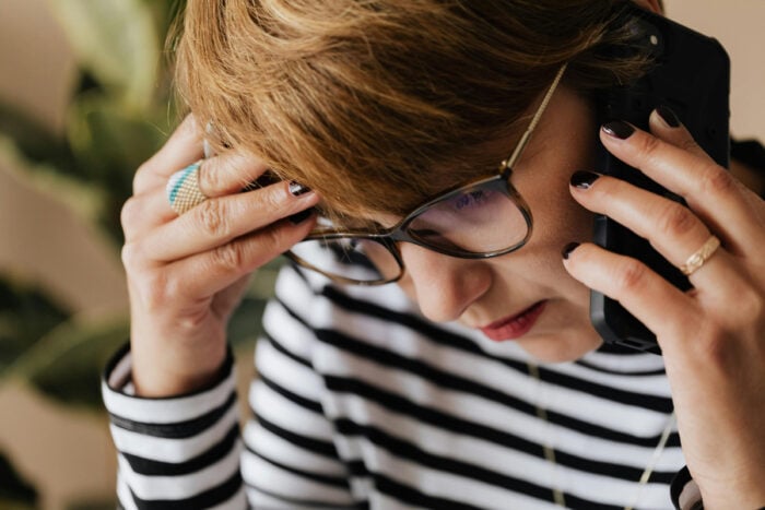 Femme au téléphone posant des questions à sa mutuelle avant une cure thermale