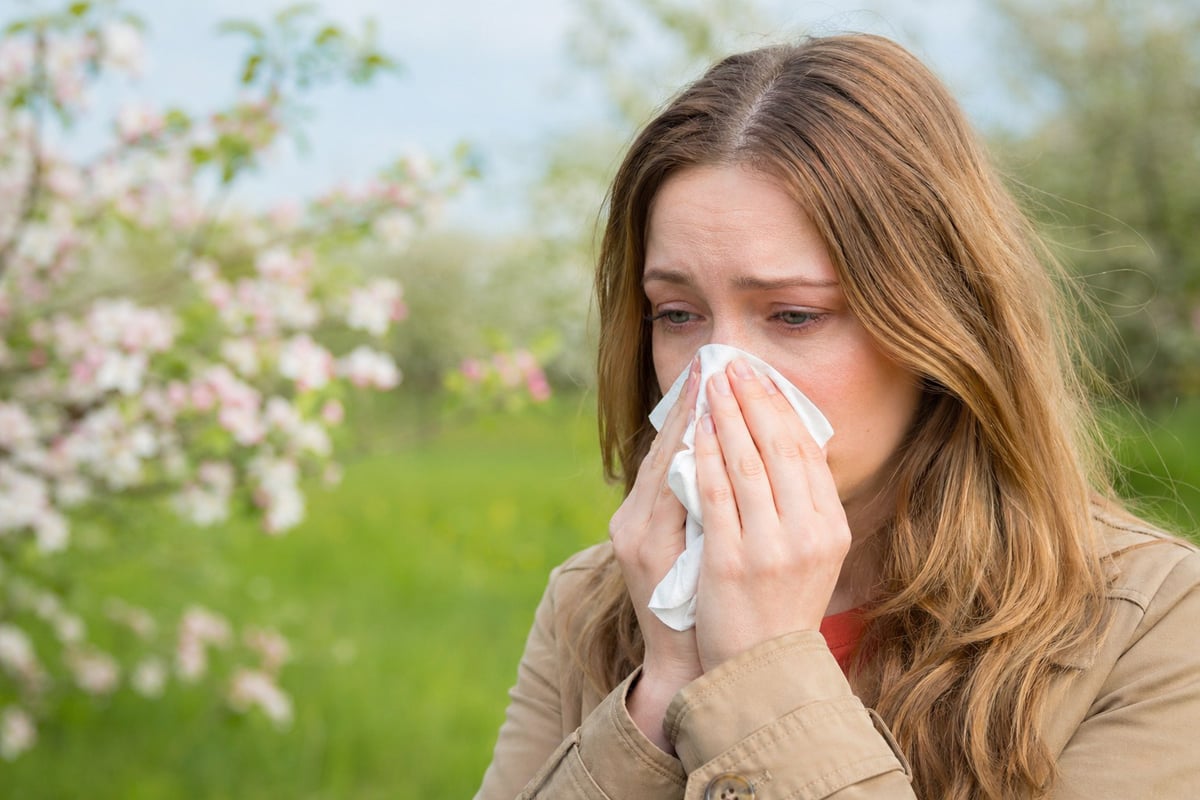 Femme souffrant d'une allergie au pollen en train de se moucher
