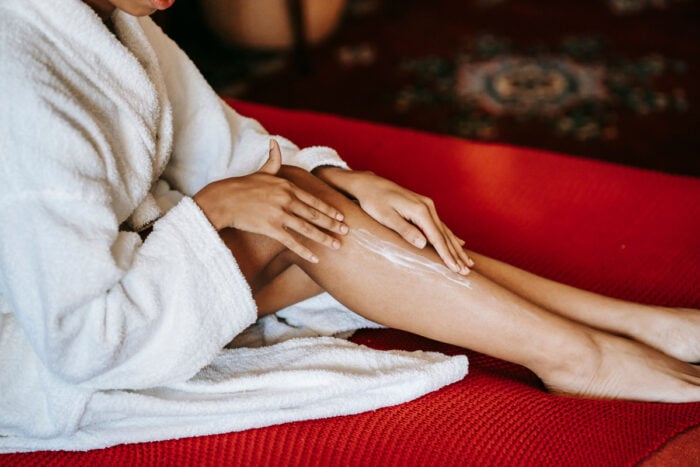 Femme en peignoir en train de se masser les jambes © Pexels / Sora Shimazaki