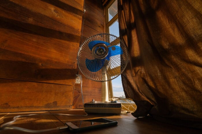 Ventilateur devant une fenêtre aux rideaux fermés © Pexels / Dương Nhân