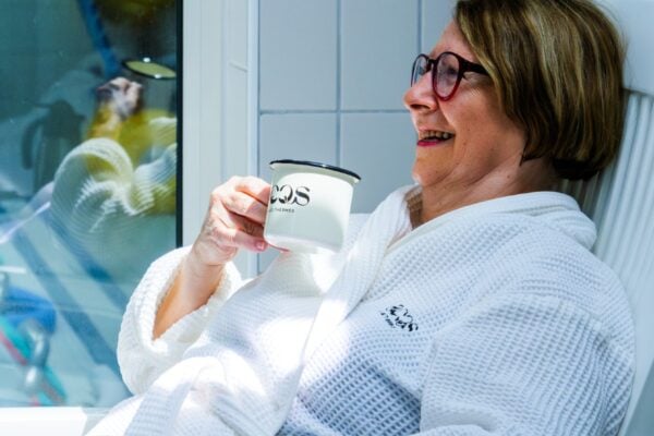 Curiste en peignoir avec tasse sur transat pendant repos après soin