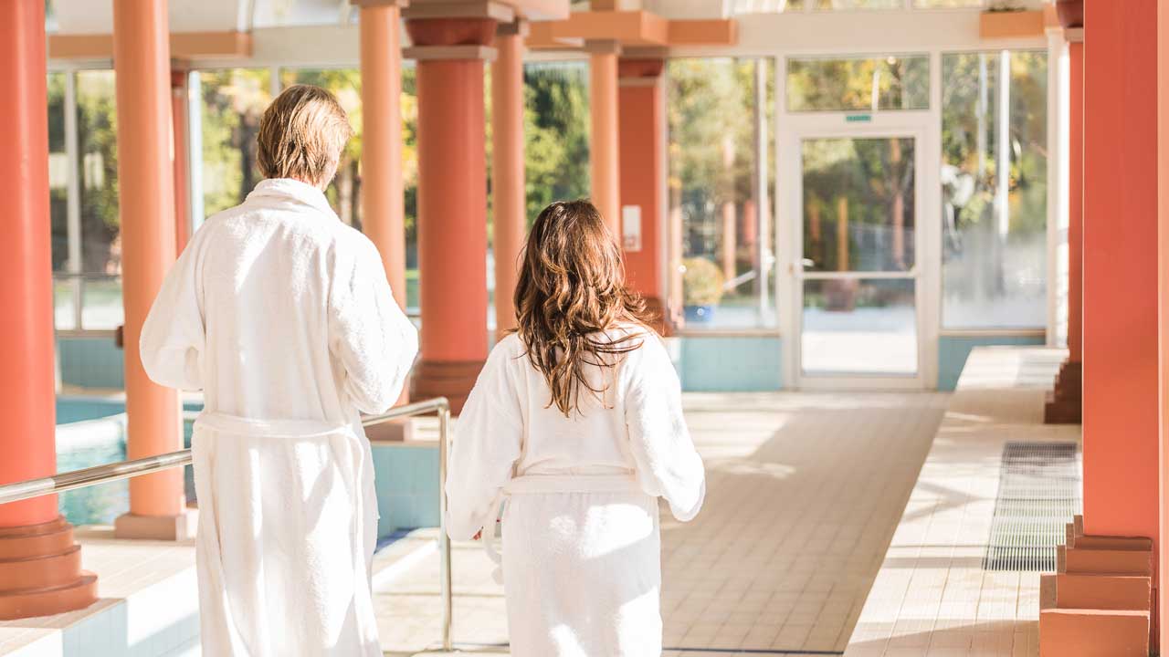 Couple de curistes de dos en peignoir le long de la piscine aux thermes Borda à Dax