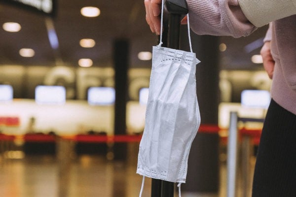 Main tenant un masque et une valise