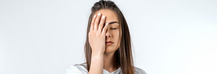 Le syndrome de fatigue chronique se caractérise par un ensemble de symptômes variés dont une fatigabilité importante ou des troubles de la mémoire et de la concentration. Femme se frottant la tête à cause de la fatigue