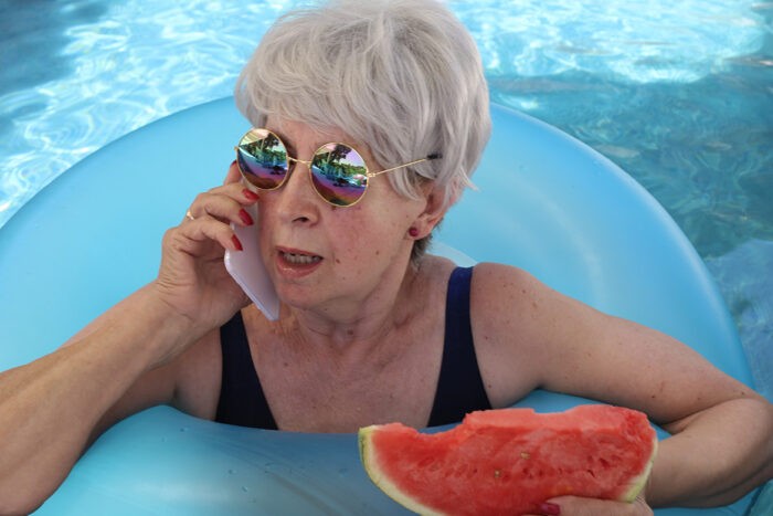 Femme dans une piscine avec un téléphone et une pastèque