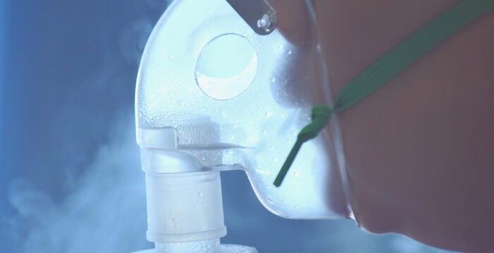 Curiste inhalant de l'eau thermale pour ses bronches