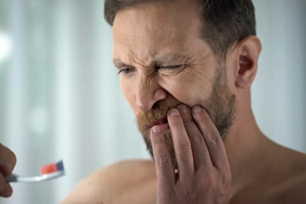 Homme se brossant les dents avec douleurs