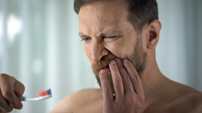 Homme se brossant les dents avec douleurs