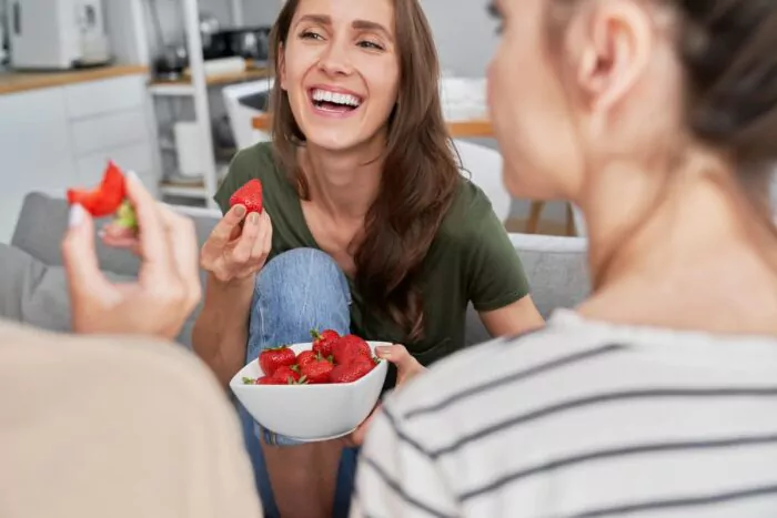 Jeunes femmes souriantes et partageant des fraises 