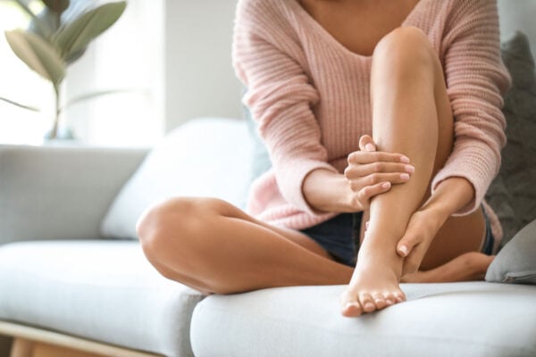 femme assise sur un canapé se tenant la jambe