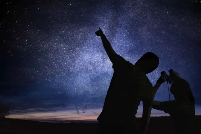 2 personnes observant un ciel étoilé avec des jumelles 