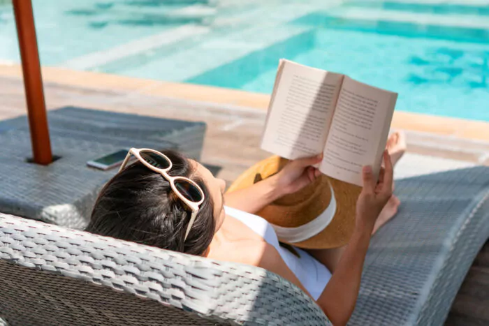jeune femme en train de lire un roman au bord de la piscine