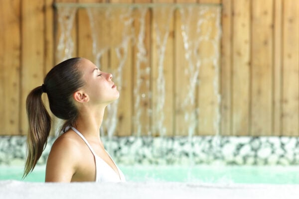 Jeune femme de profil cheveux attachés détendus dans une piscine