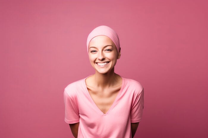 Jeune femme de face avec un t-shirt rose et un foulard rose sur la tête sur fond rose