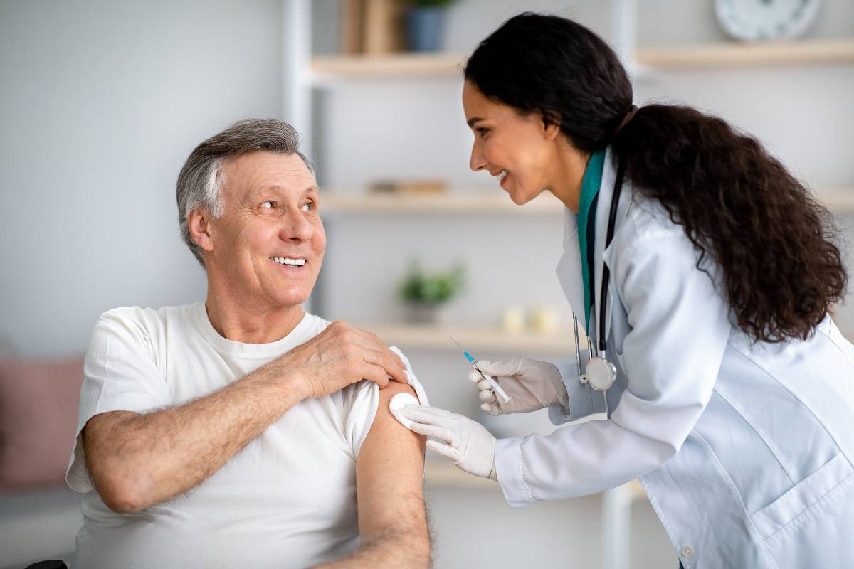 Homme souriant se faisant vacciner par une infirmière