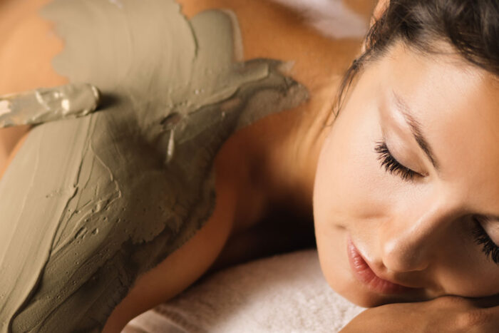 jeune massage sur le ventre allongée détendue avec un massage du dos à la boue