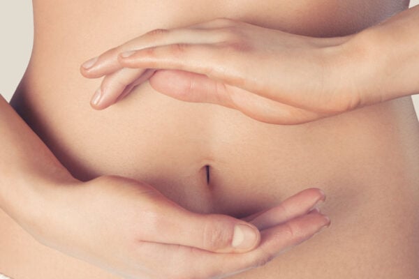 Ventre d'une femme de face avec une main en dessous du nombril et l'autre en dessus