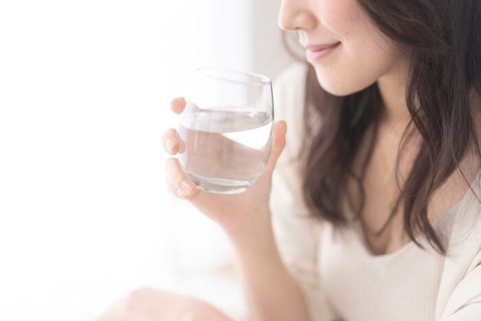 Femme de profil qui tient un verre d'eau à la main