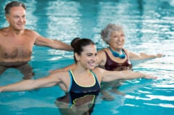 Trois personnes dans une piscine faisant des exercices