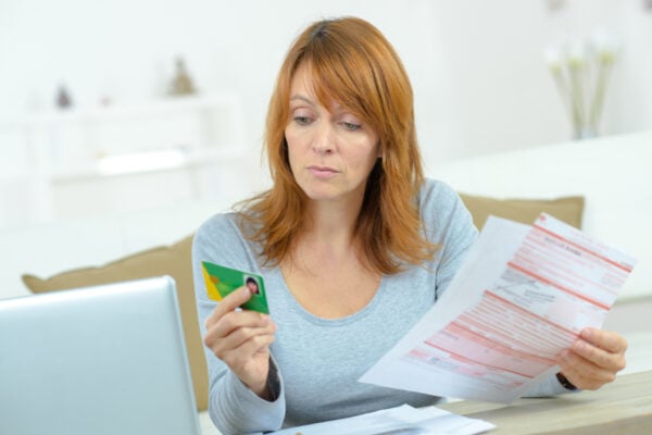Femme tenant sa carte vitale dans la main droite et la feuille de soin à remplir dans la main gauche
