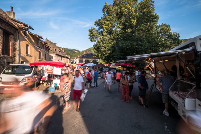 Allée d'un marché avec de nombreux passants en Aveyron