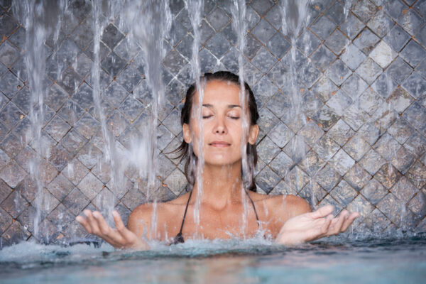 Femme sous une cascade d'eau dans un spa thermal