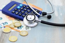 Une calculatrice, quelques billets et un stéthoscope posés sur une table