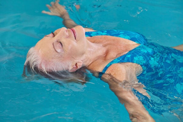 Femme détendue flottant sur le dos dans une piscine