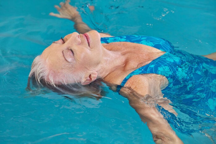 Femme détendue flottant sur le dos dans une piscine