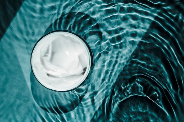 Pot de crème vue de haut posé sur un sol submergé d'eau