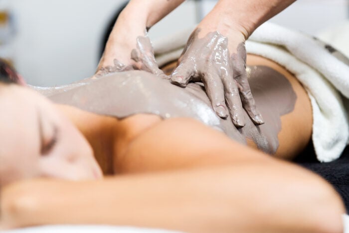 Femme en soin dans un spa thermal, application de boue sur le dos