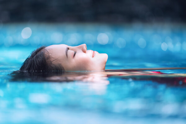 Jeune femme flottant sur le dos dans une piscine