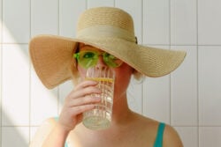Femme avec un chapeau et des lunettes de soleil en train de boire pour éviter la déshydratation liée aux fortes chaleurs © Pexels - Ksenia Chernaya